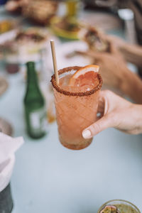 Hand of man holding glass of fresh cocktail at restaurant