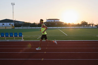 Young man trains running on new and red tracks