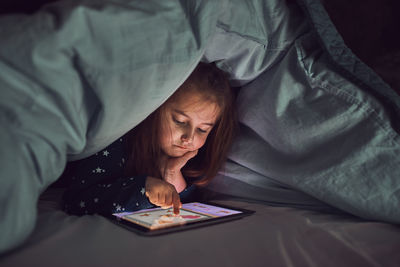 Little girl having fun watching, playing and listening to stories on tablet computer