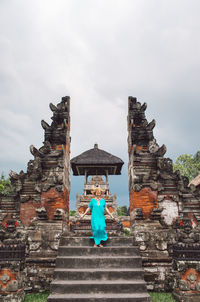 Long angle view of woman standing on a stairs in front of a temple gate