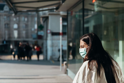 Woman wearing mask looking away while standing outdoors