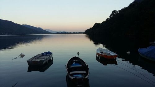 Boats moored on lake against sky during sunset