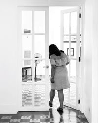 Rear view of woman standing against door at home