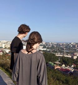 Two teenagers standing on mountain and watching the cityscape
