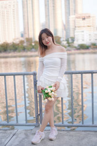 Side view of young woman standing by railing