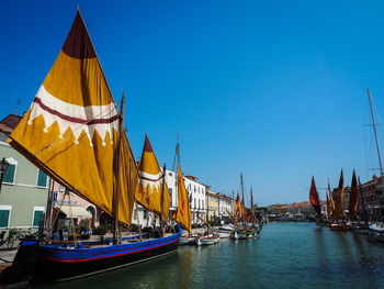 Sailboats in water against clear blue sky