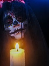 Close-up portrait of woman with illuminated candle