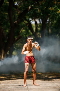 Full length of shirtless warrior standing in forest