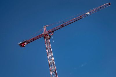 Low angle view of crane against clear blue sky