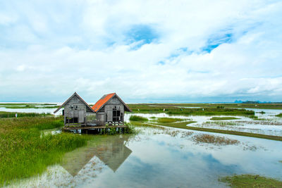 House on field by building against sky