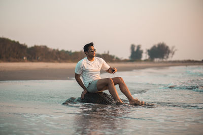 Side view of shirtless boy playing in lake