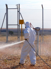 Man spraying water on field against sky