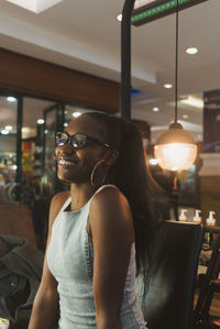 Young woman looking away while standing in illuminated room