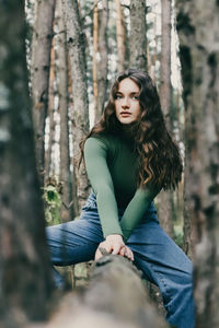 Young woman sitting on tree trunk