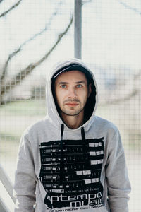 Portrait of man standing by fence