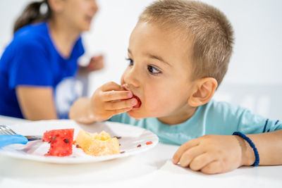 Cute boy looking away while eating fruits in plate