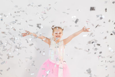 Full length of happy girl with arms raised in background