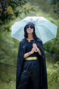 Portrait of young woman with umbrella standing outdoors