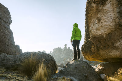 Rear view of man standing on rock against sky