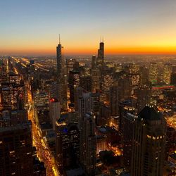 Aerial view of illuminated city buildings during sunset