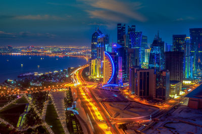 Illuminated modern buildings in city against sky at night