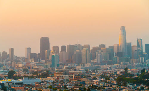 Modern buildings in city against clear sky during sunset