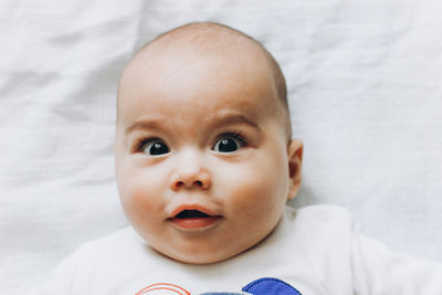 Portrait of cute baby boy lying down on bed