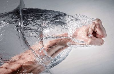 Digital composite image of man punching water against wall