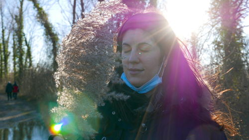 Portrait of smiling young woman against trees