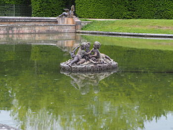 Statue on lake against trees