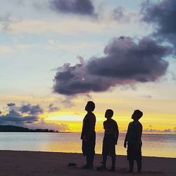 Rear view of silhouette people on beach at sunset