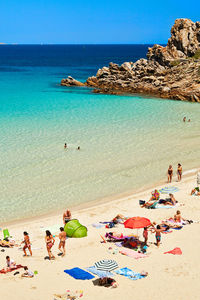 People on beach against clear blue sky