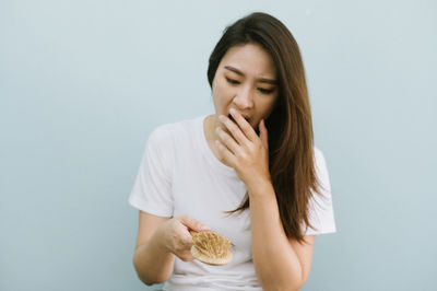 Young woman eating food against white background