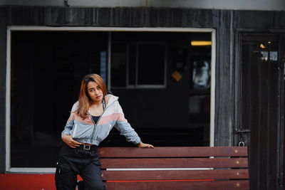 Portrait of smiling young woman standing against building