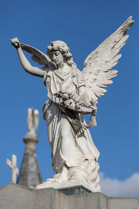 Low angle view of angel statue against blue sky