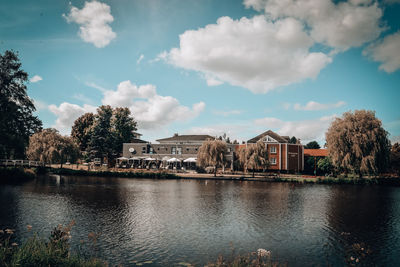 Houses by lake and buildings against sky