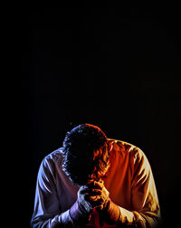 Depressed man standing against black background