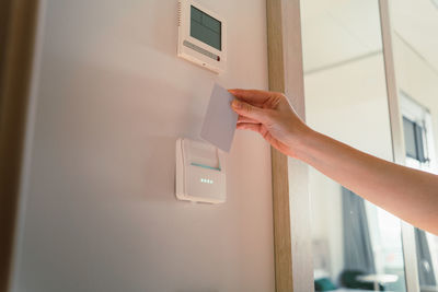 From below of crop anonymous female tourist putting card key into into switch in modern hotel room in daytime