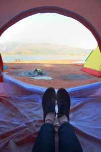 Low section of person relaxing on land in tent