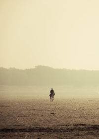 Silhouette man walking on shore against clear sky