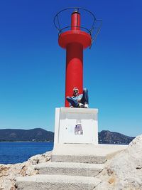 Lighthouse against clear blue sky and one man in front 