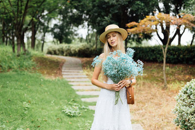 Portrait of young woman standing against plants