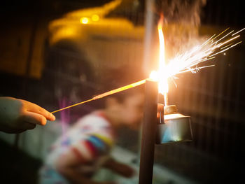 Close-up of hand holding lit candles