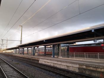 Railroad tracks at station against cloudy sky