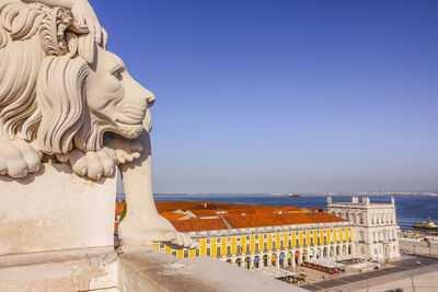 Statue by sea against clear blue sky