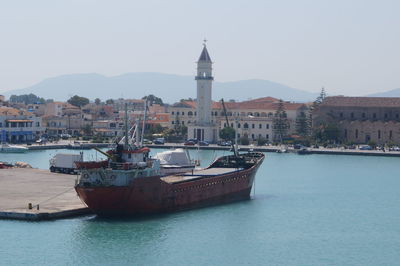 Boats in sea by city against clear sky