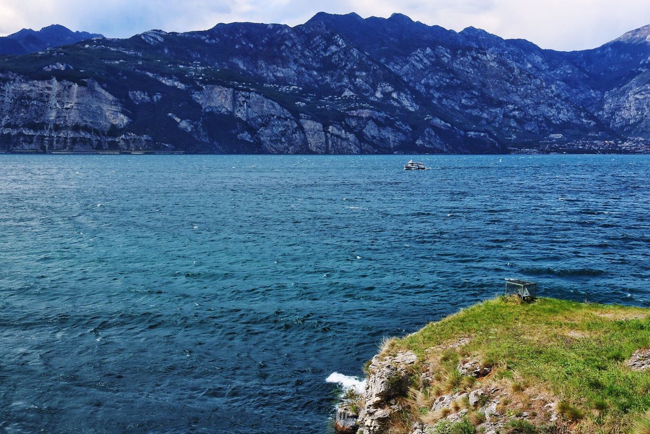 nature, beauty in nature, mountain, water, scenics, sea, tranquil scene, tranquility, outdoors, rock - object, day, idyllic, mountain range, blue, cliff, no people, vacations, tree, sky, nautical vessel, animal themes