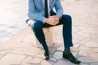 Low section of man sitting on footpath