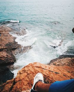 Low section of man standing on rock by sea