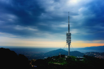 Communications tower against cloudy sky